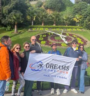 eine Gruppe von Menschen, die ein Schild vor einem Garten halten