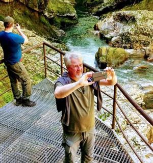 two men standing on a bridge taking a picture of a river