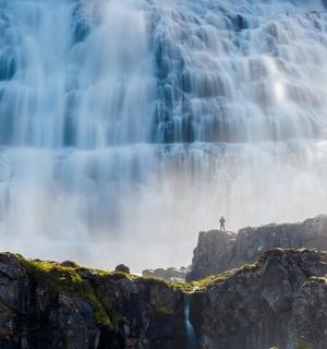 站在瀑布前岩石上的人