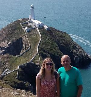 a man and woman standing in front of a lighthouse