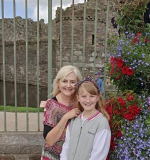a woman and a young girl standing in front of flowers
