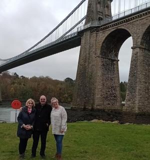 a group of three people standing in front of a bridge