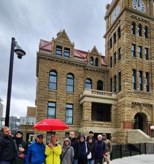 eine Gruppe von Menschen steht vor einem Gebäude mit einem Uhrenturm