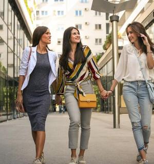 tre kvinder går ned ad en gade i en by