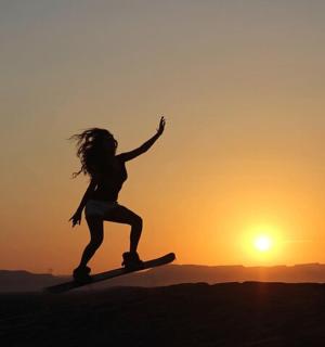Dívka skáče na surfu při západu slunce