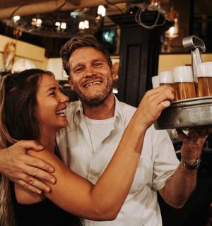 a man and a woman holding a tray ofbeer