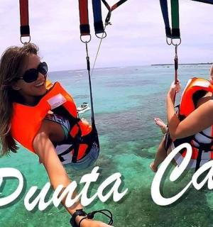 two girls riding on a zip line over the ocean