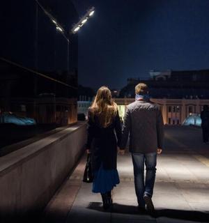a man and woman walking down a bridge at night