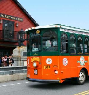 一辆橙色和绿色的巴士驶过一座红色建筑