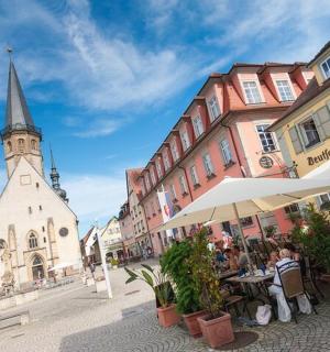 eine Gruppe von Menschen sitzt an Tischen auf einer Straße mit einer Kirche