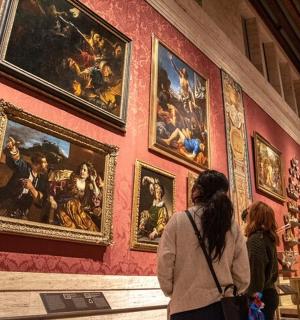 skupina lidí prohlížejících si zeď s obrazy