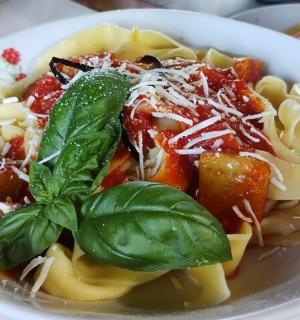 a white bowl of pasta with basil on top