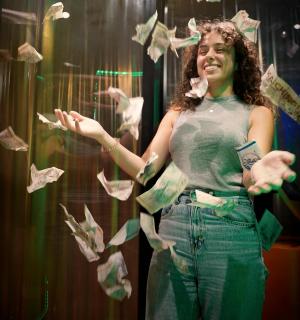 a woman standing in a room with money flying around