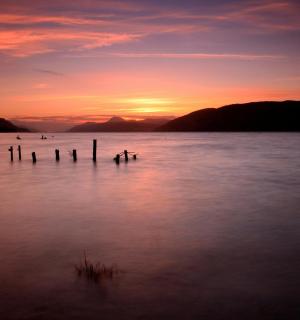 a sunset on a lake with poles in the water