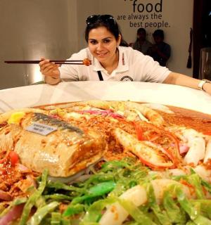 a woman holding a chopstick in front of a plate of food