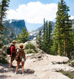two people walking on a trail in the mountains