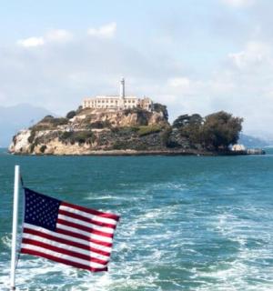 an island with a lighthouse and an american flag on a boat
