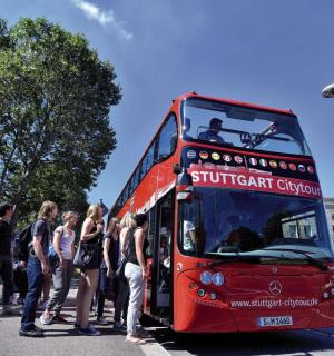 skupina lidí nastupujících do červeného dvoupatrového autobusu