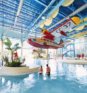 a large indoor pool with an airplane hanging from the ceiling