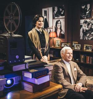an older man sitting next to a pile of books