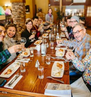 一群人坐在桌边，手里拿着酒杯