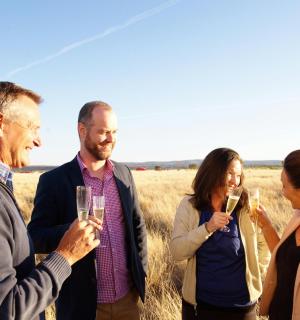 一群人站在田野里，手里拿着香槟酒杯