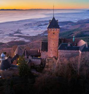 a castle on a hill with a sunset in the background