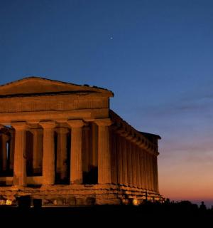 a building with columns in front of a sunset