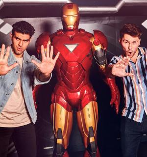 a group of three men standing next to a spider man costume