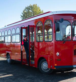一辆红色巴士，车门上站着一名男子