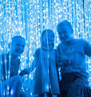 two boys sitting in front of a wall with lights