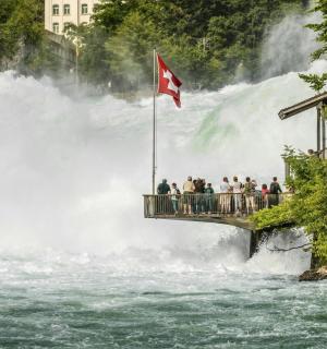 skupina lidí stojící na mostě před vodopádem