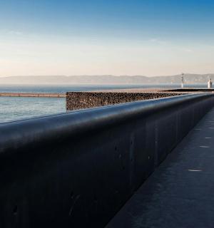 a long black fence next to the water