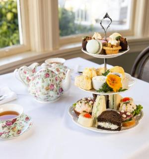 一张桌子上摆着三层甜点和一杯茶