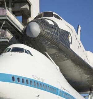 an airplane parked next to a building with a shuttle