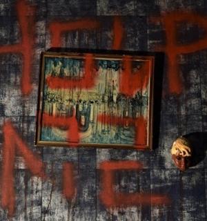 墙上有一幅骷髅画，上面有红色的涂鸦