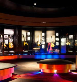 místnost s hromadou vystavených kytar