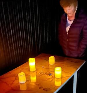 a woman standing next to a table with yellow candles on it