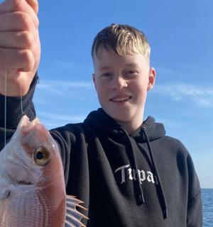 ein kleiner Junge hält einen Fisch in der Hand
