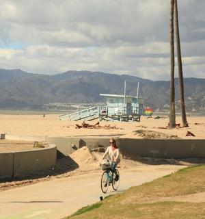 a person riding a bike on a path next to a beach