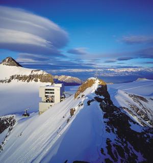 zasněžená hora s budovou na vrcholu
