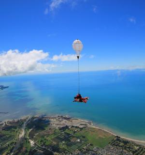 člověk visí z horkovzdušného balónu nad vodou