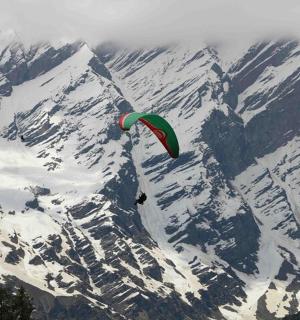 a person flying a kite over a snow covered mountain