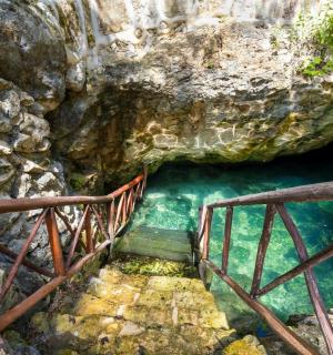 a stairway leading to a cave with blue water