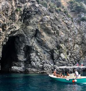 skupina lidí na lodi před jeskyní