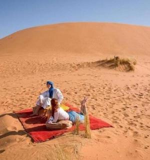 两个人坐在沙漠中的毯子上