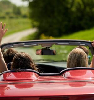 a group of people in a car with their arms up