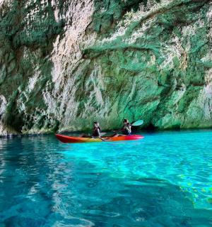 两个人在悬崖边的水中划皮划艇