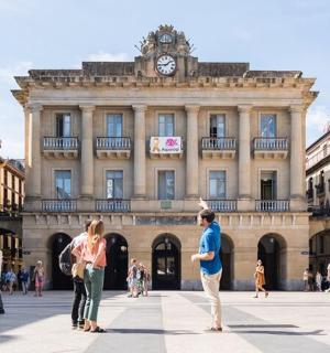 un grup de persones dretes davant d'un edifici amb una torre del rellotge