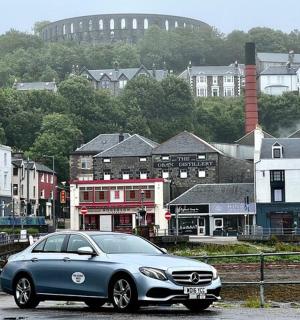 a blue car parked in front of a city